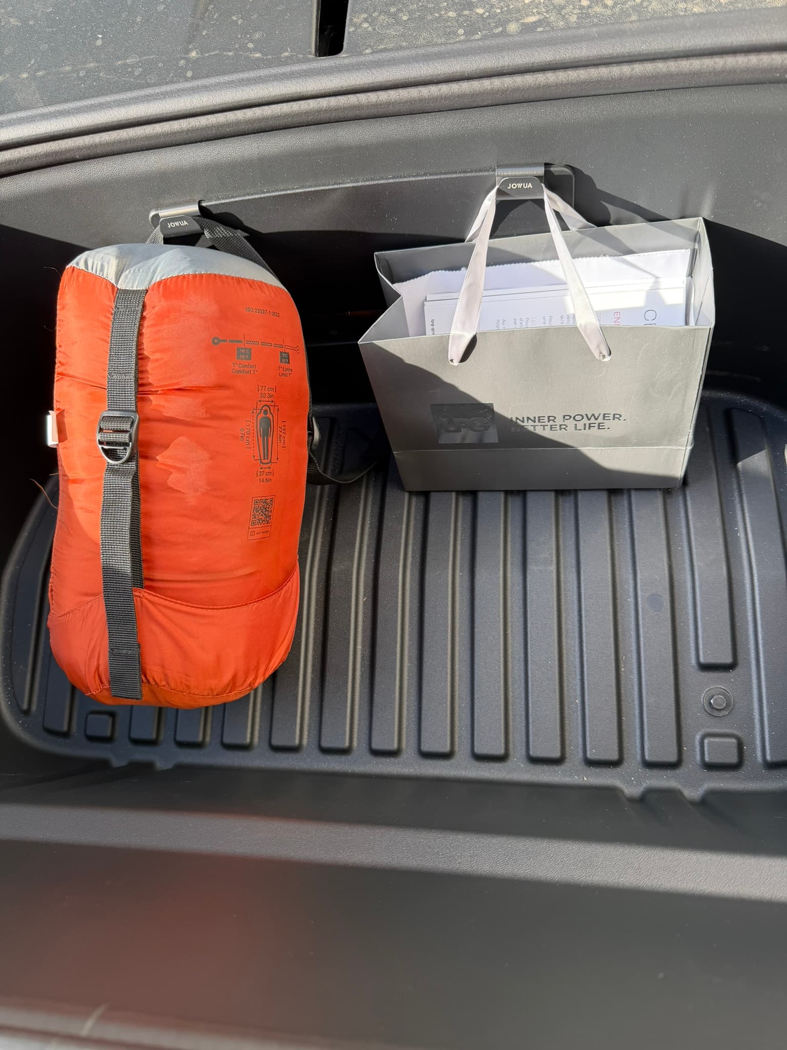 Les deux crochets Jowua fixés dans le frunk de ma Tesla Model Y Juniper, avec un sac de couchage et un sac suspendus